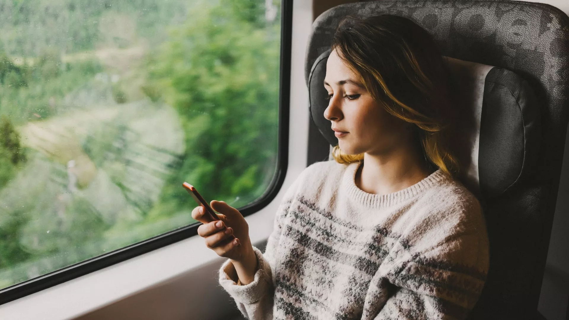woman using phone on train while abroad to roam